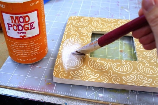 Add Mod Podge to the front of the scrapbook paper on the frame
