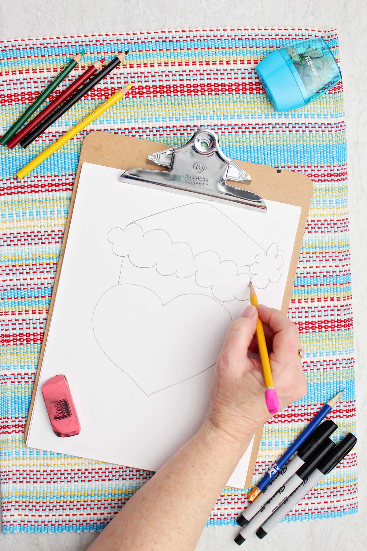 Person adding some trim details on the Santa hat of their Grinch sketch.