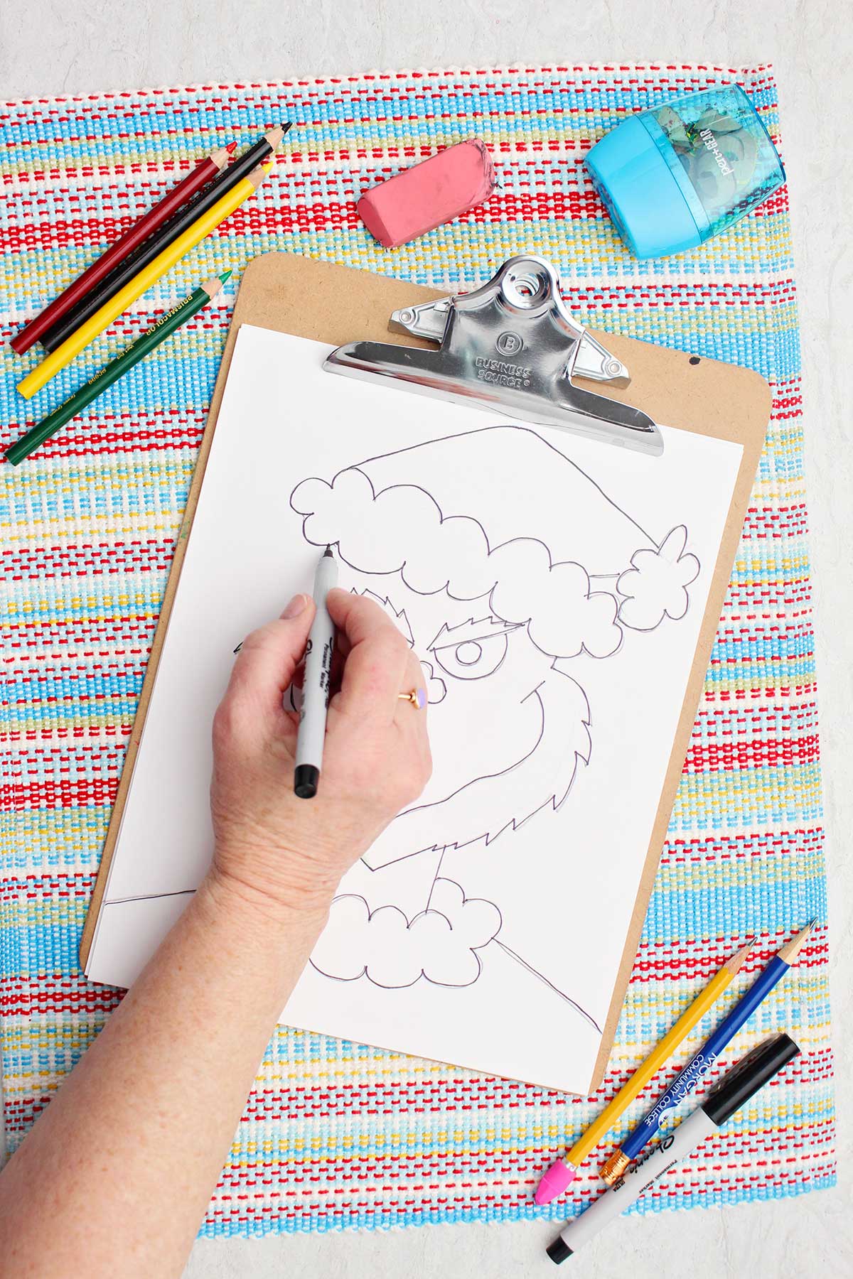 A person going over the pencil sketch of The Grinch in Sharpie marker.