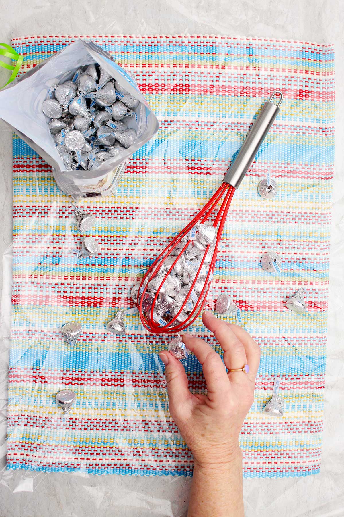 Person placing Hershey Kisses inside of a red silicone whisk.