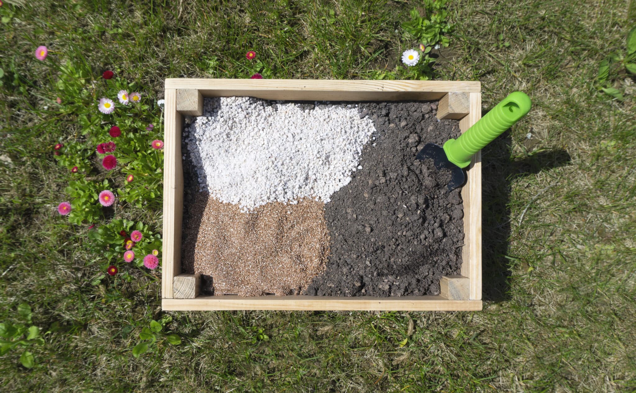 A wooden box in the garden, filled with soil and organic amendments before being mixed.
