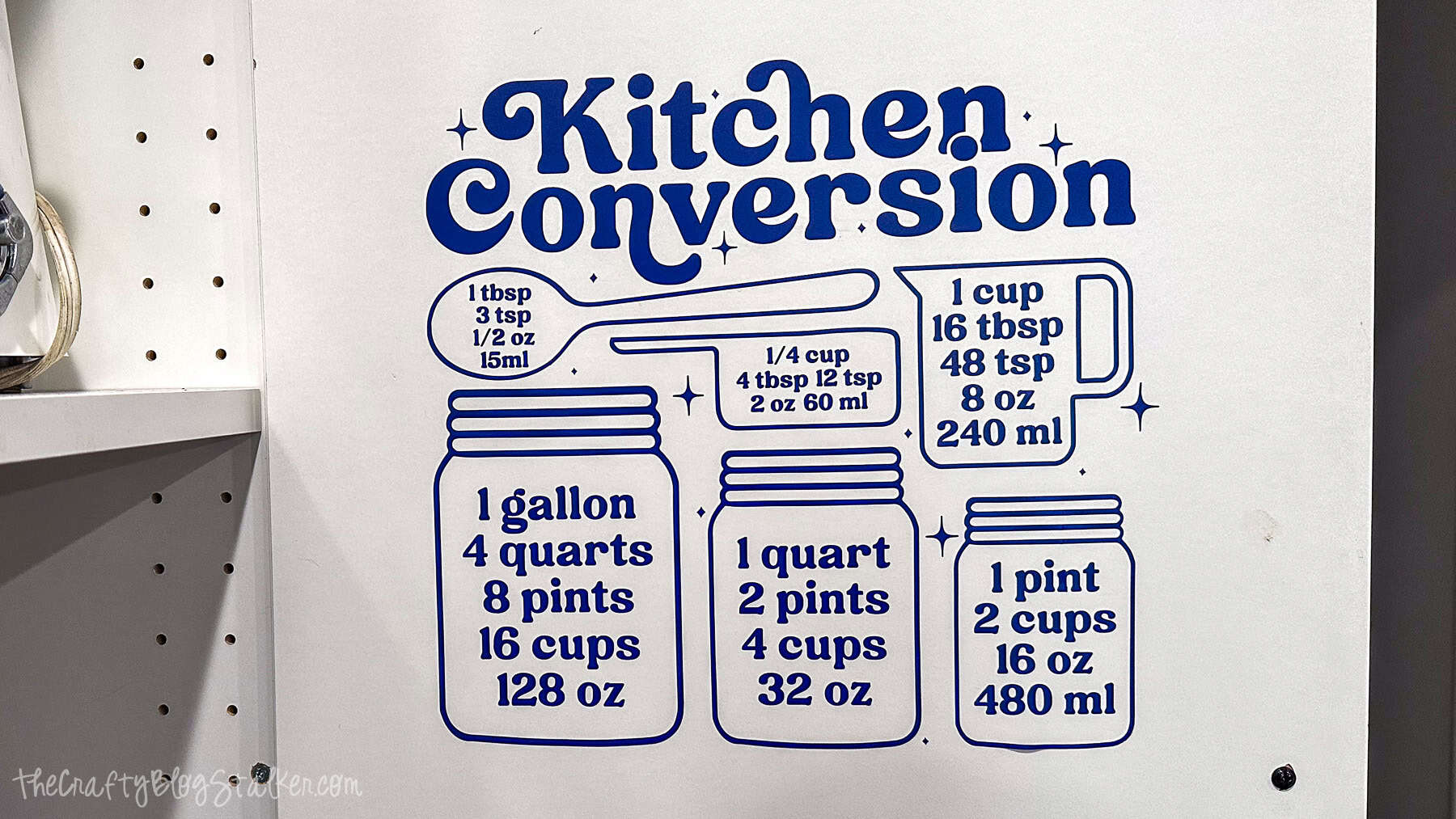 Blue kitchen conversion chart vinyl decal applied to a wall showing tablespoon, cup, pint, quart, and gallon measurements with jar and measuring tool graphics.