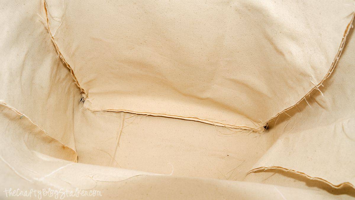 Inside view of canvas tote bag with stitched seams and boxed corners showing raw edges before finishing the bag.