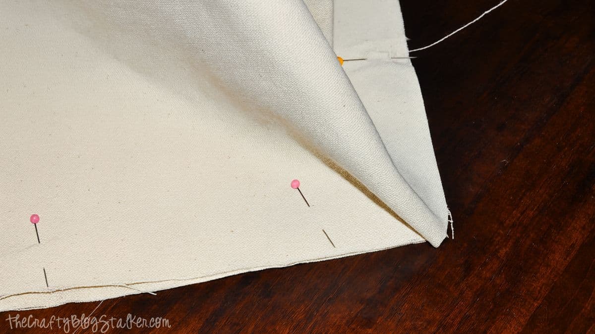 Canvas tote bag fabric pieces pinned together along the bottom edge before sewing the seam.