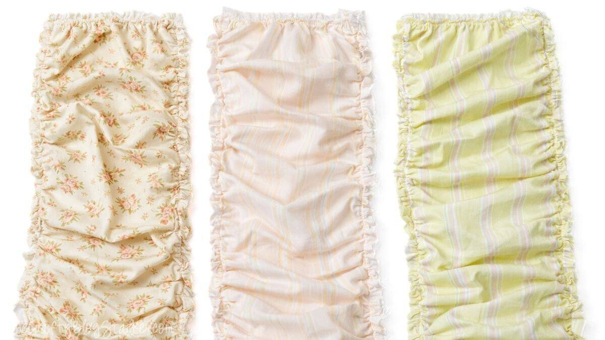 Three ruffled fabric strips laid side by side, showing gathered edges and different patterned fabrics prepared for a doll quilt project.