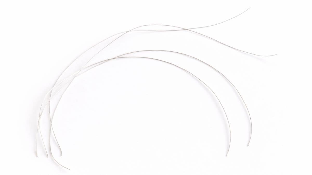 Four pieces of thin craft wire laid out on a plain background, cut to equal lengths for jewelry making or DIY projects.