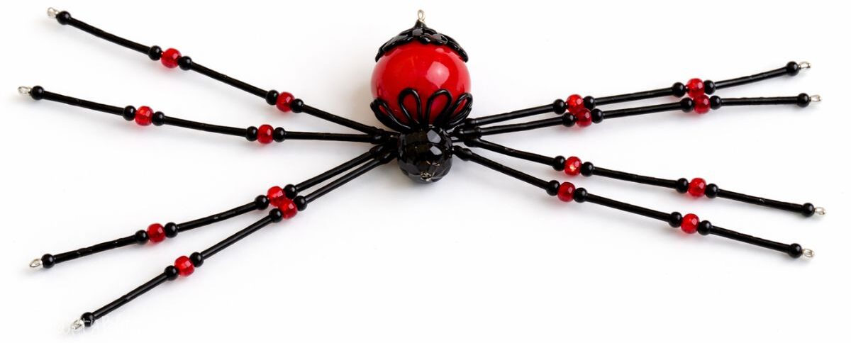 Fully assembled beaded spider craft with wire legs and bead body laid flat on a plain background as a finished DIY decoration.