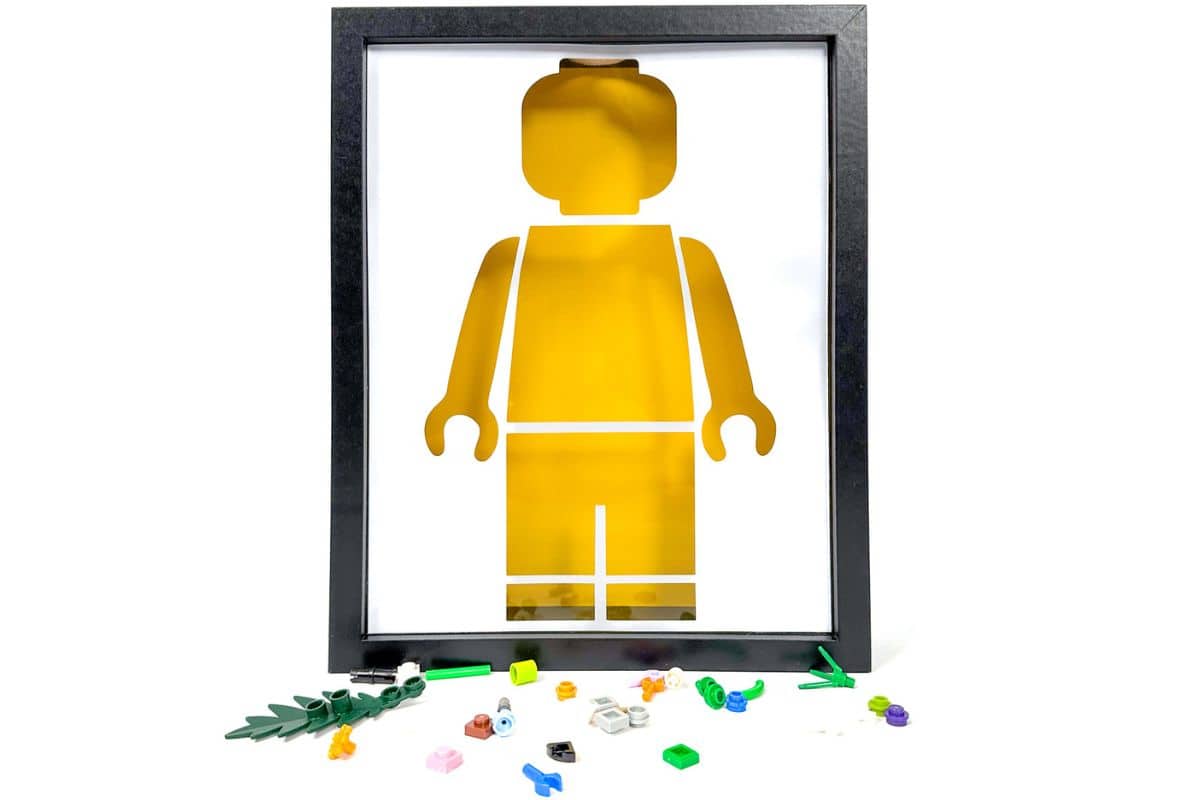 Framed yellow LEGO figure silhouette with scattered colorful LEGO pieces below, showcasing a creative DIY design idea.