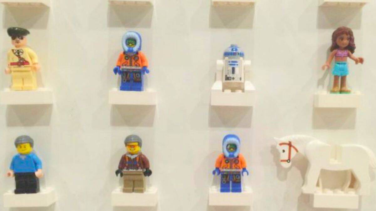 LEGO minifigures displayed on small wall-mounted shelves, arranged in a neat grid for organized storage and display.