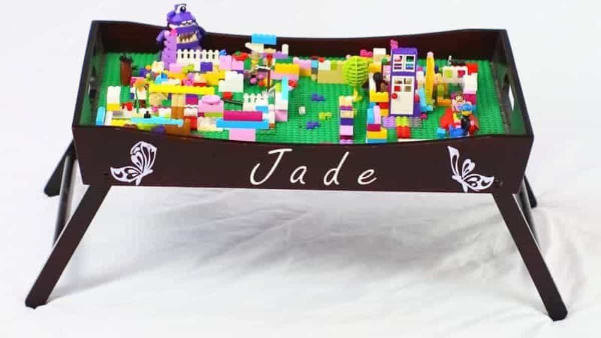 Personalized LEGO play tray table filled with colorful LEGO bricks and builds, featuring a raised edge and the name Jade on the front.
