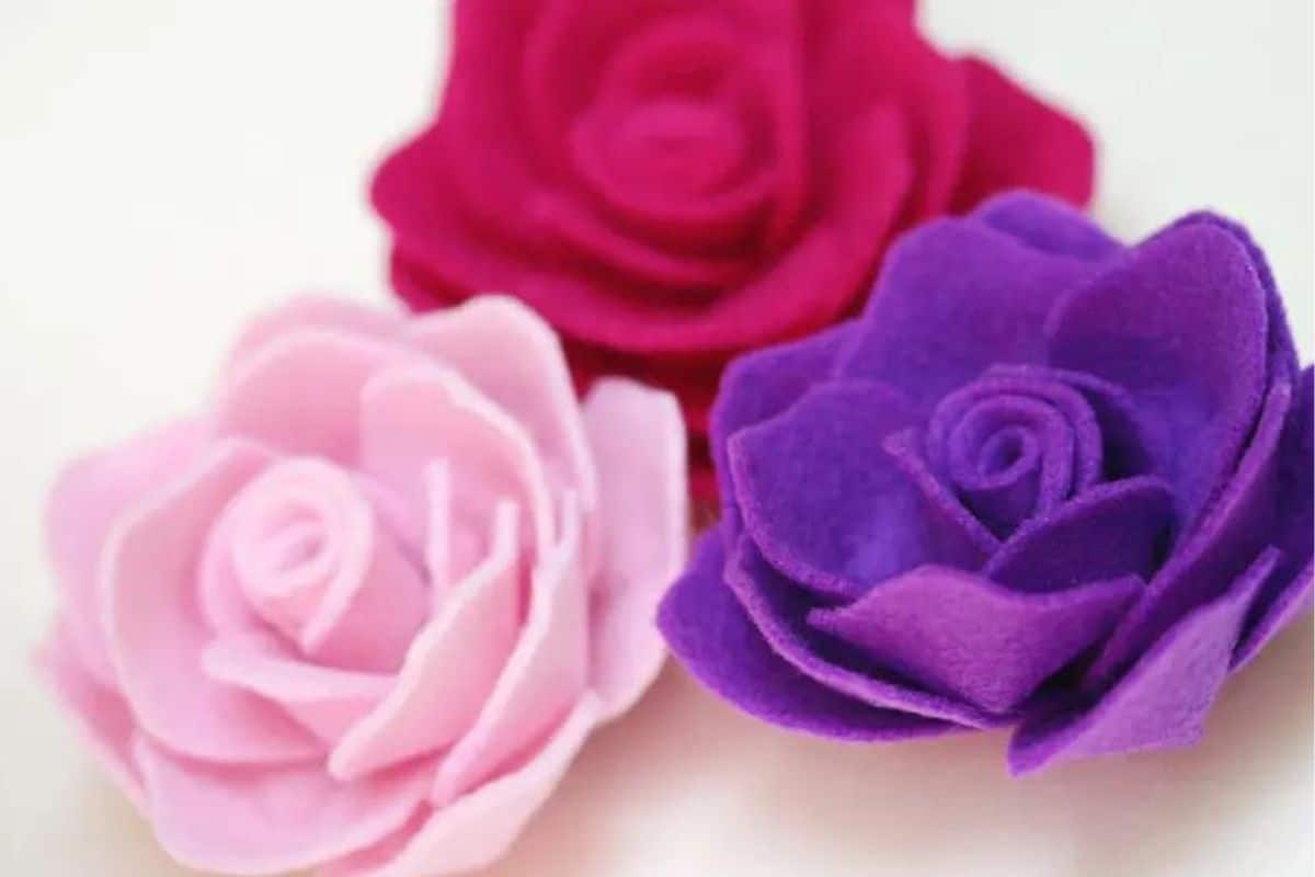 Three handmade felt roses with layered petals, arranged together on a light background as a simple craft or embellishment example.