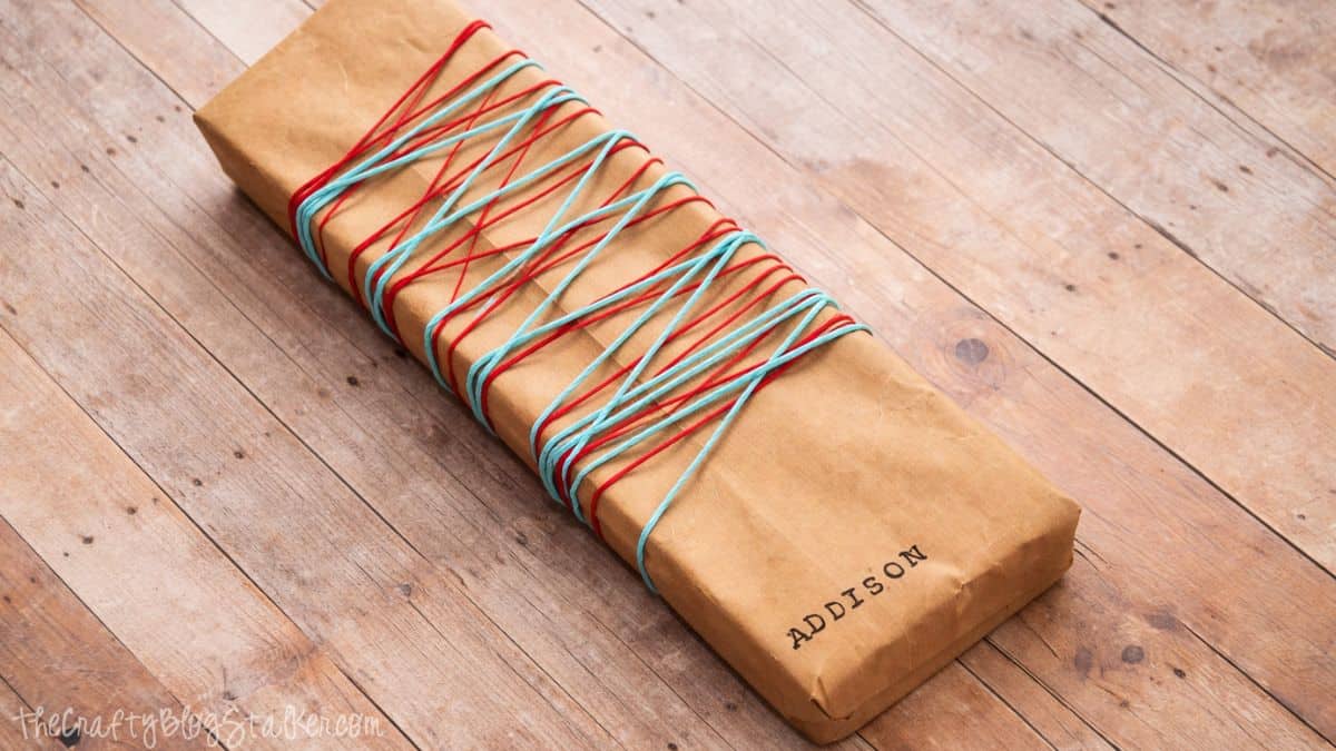 Rectangular gift neatly wrapped in kraft paper, placed on a wooden surface, showing simple and minimalist gift wrapping.