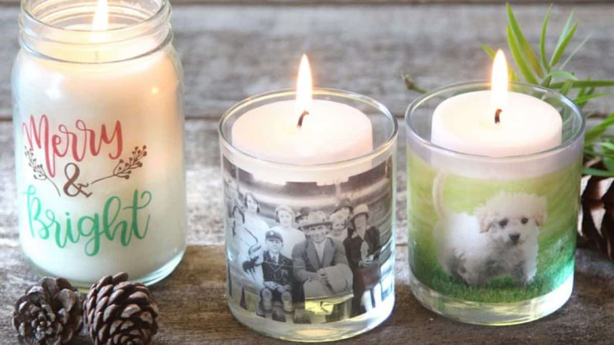 Three candles displayed on a rustic surface, including two votives wrapped with personal photos and one jar candle with a festive design.