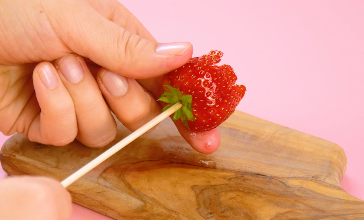 Insert the wooden skewer through the stalk into the strawberry