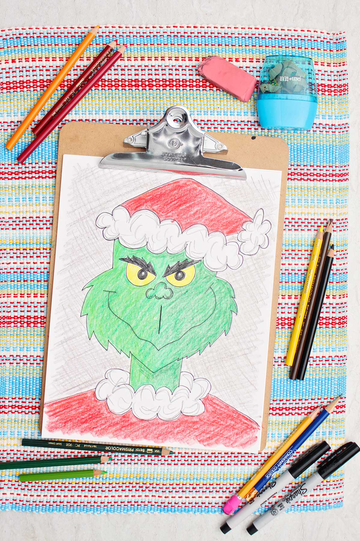 Colored in version of a Grinch sketch with colored pencils near by.