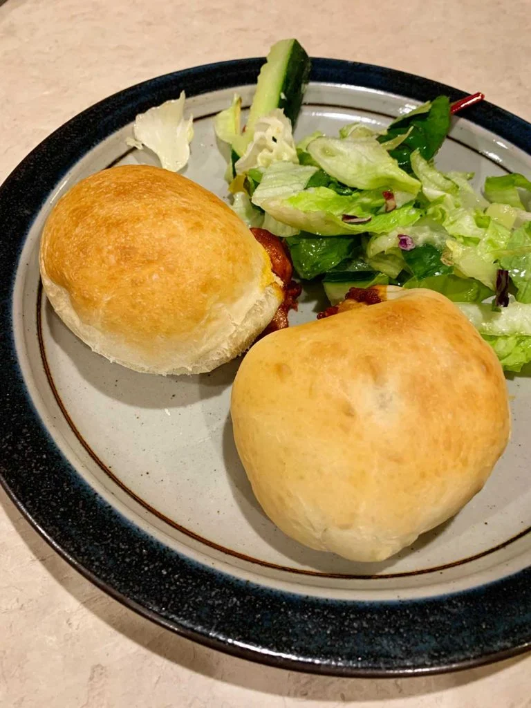 Homemade pizza pockets on a dinner plate with a salad.