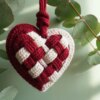 dänisches Herz häkeln: ein rot-weißes Herz mit Schachbrettmuster vor einer grünen Wand und Eukalyptuszweigen