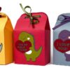 Three handmade Valentine treat boxes shaped like small gift cartons, each decorated with a cute dinosaur holding a heart and tied with ribbon on top.
